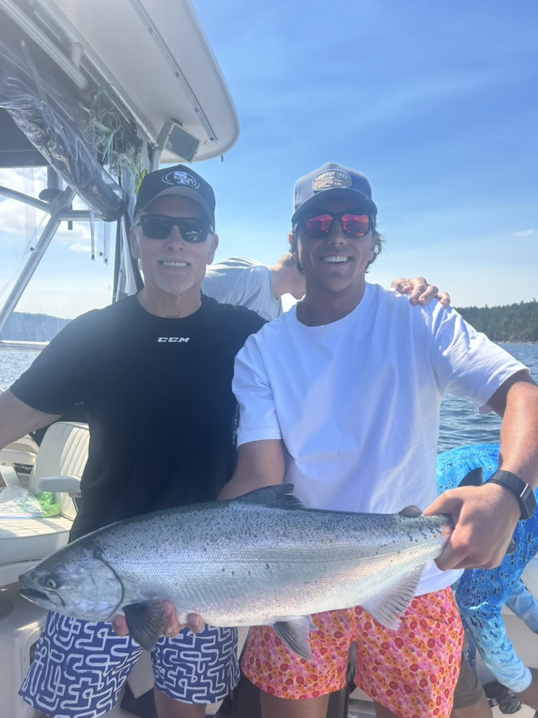 Justin holding a large salmon on a boat near Vancouver